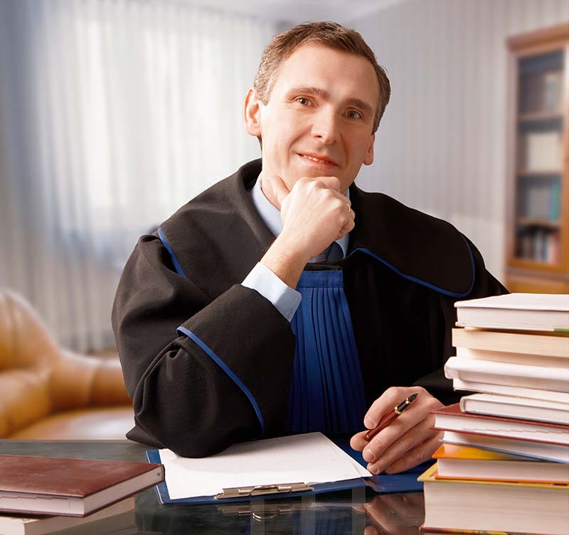 judge sitting at desk with a lot of books on it