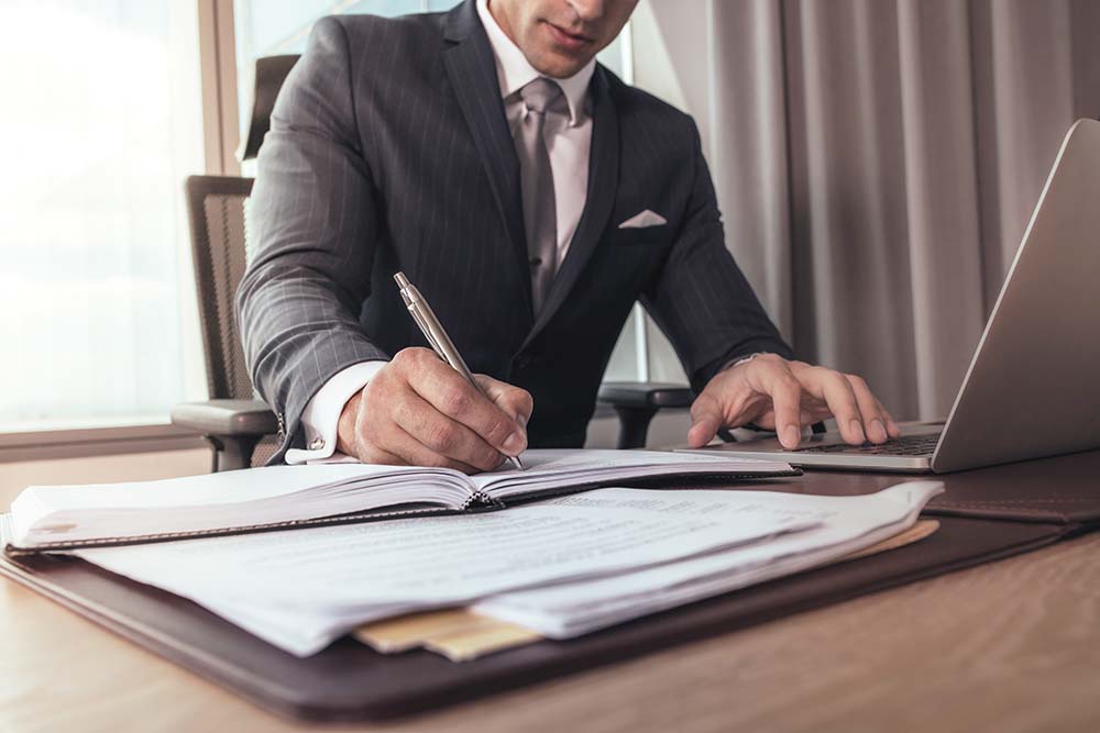 attorney sitting at desk in front of laptop computer in his law firm office
