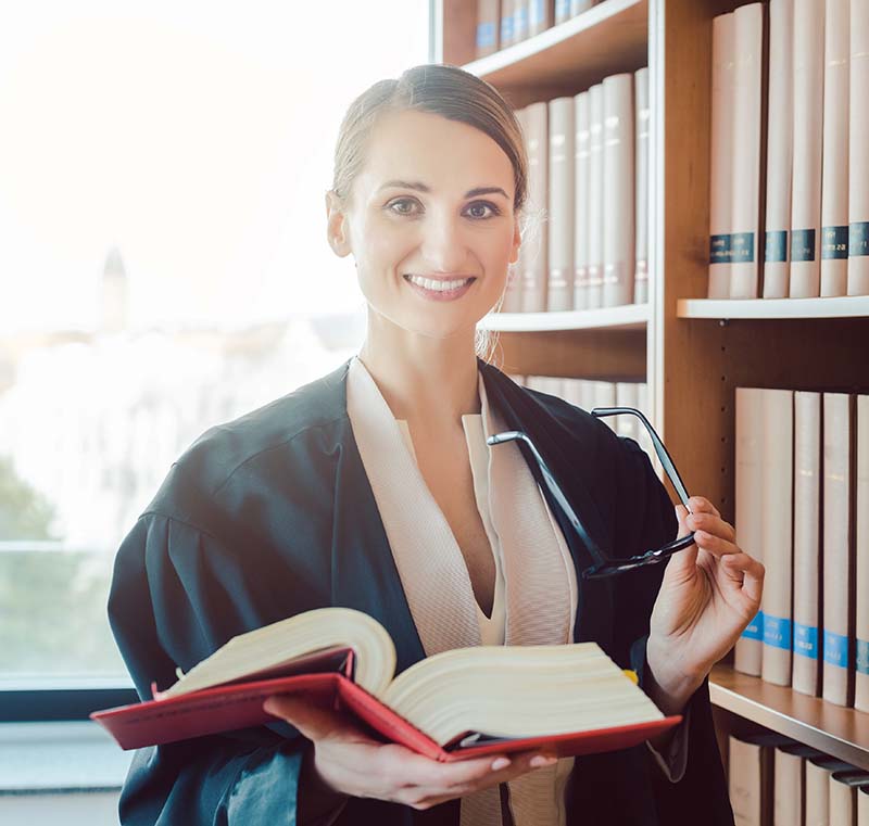 female attorney in law firm library holding a legal book