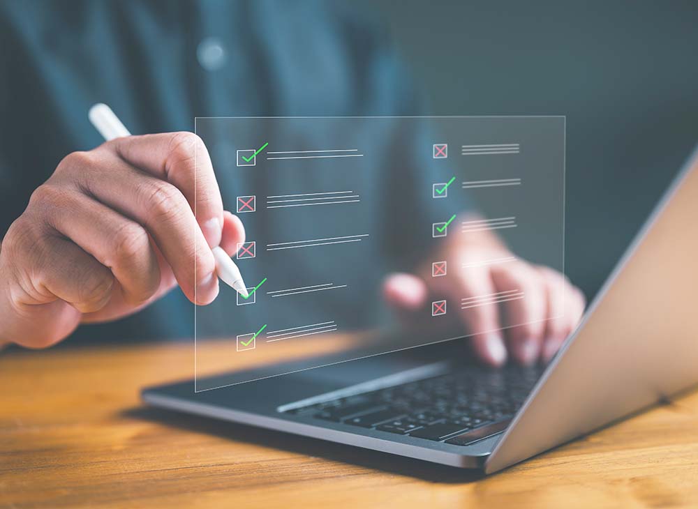 man sitting at desk using laptop while a checklist appears over the laptop