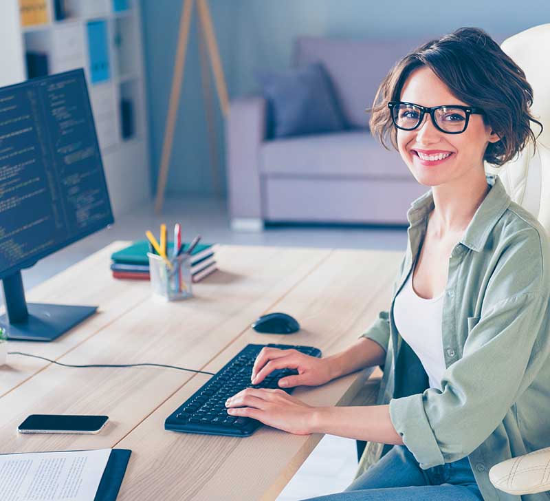 young woman sitting at her desk with hands on her keyboard coding a website