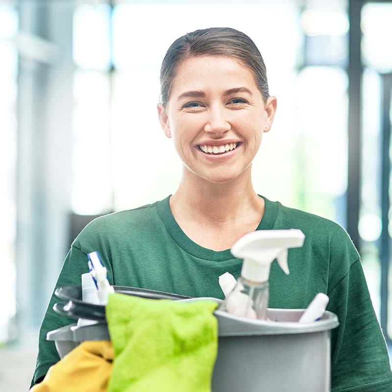a woman cleaning services employee happy while holding a bucket of cleaning supplies