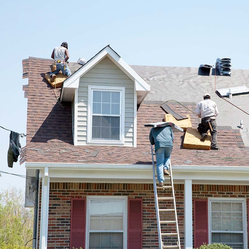 three roofers on top of a home installing a roof for a client