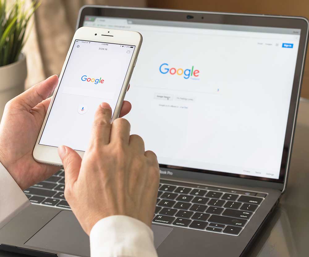 Google search engine sign up page on mobile app touchscreen on iphone in business person's hand and on computer screen display