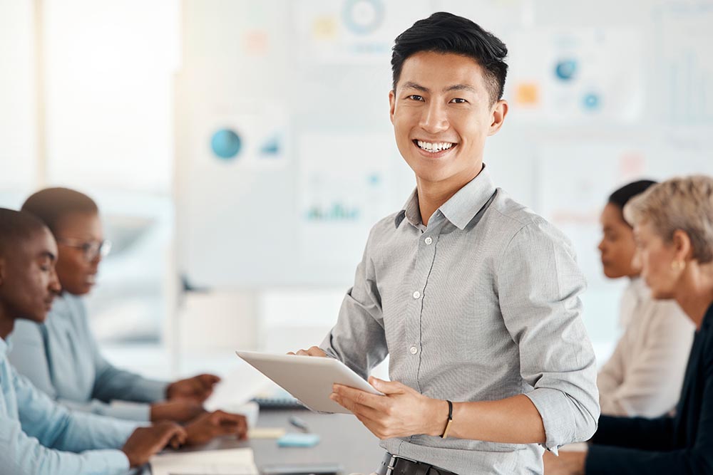 Workshop, portrait and businessman with a tablet in a meeting for planning, strategy and collaboration at work. Smile, digital and corporate Asian worker typing on technology during a seminar.